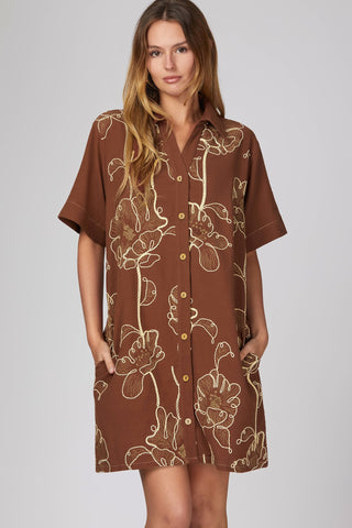 woman wearing: SHORT SLEEVE WOVEN EMBROIDERED COLLARED BUTTON DOWN MINI DRESS WITH POCKETS