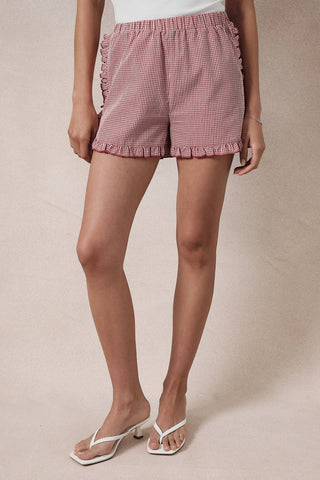 Person wearing pink checkered shorts on a beige background