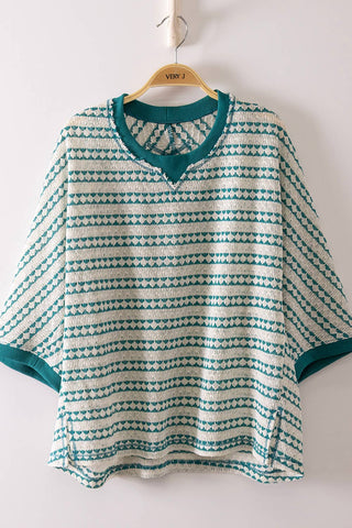 Knitted sweater with green and white pattern on a hanger against a white background