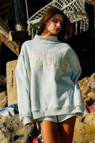 Person wearing a light gray sweatshirt with 'ESU' printed on it, standing outdoors.