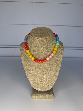Colorful beaded necklace on a mannequin bust against a plain background
