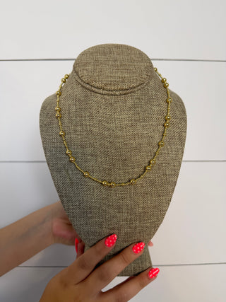 Gold necklace on a brown mannequin bust with a white background