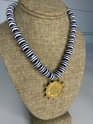 Striped necklace with a gold pendant on a mannequin bust.