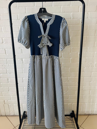 Striped dress on a hanger against a white brick wall.