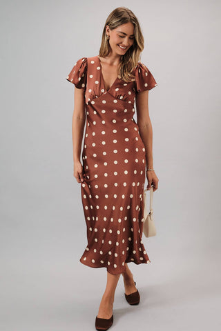 Woman wearing a brown polka dot dress on a gray background