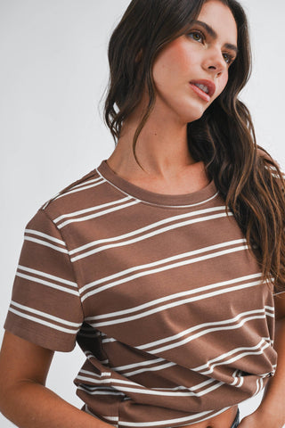 Woman wearing a brown and white striped shirt against a plain background