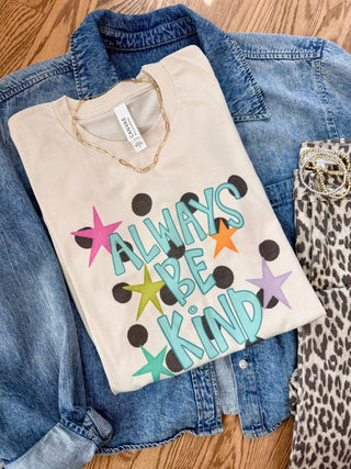 Beige sweatshirt with 'Always Be Kind' text and colorful stars on a denim jacket and leopard print pants.